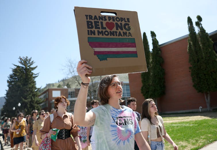Jóvenes activistas marchando con una mujer al frente sosteniendo un cartel que dice 